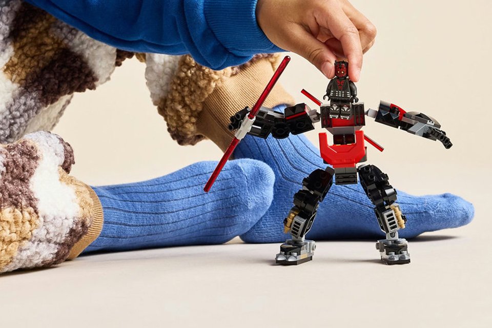 A boy playing with a LEGO Star Wars Darth Maul Mech building toy for kids.