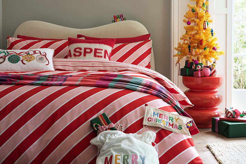 Candy striped bedding in pink and red with santa cushion.