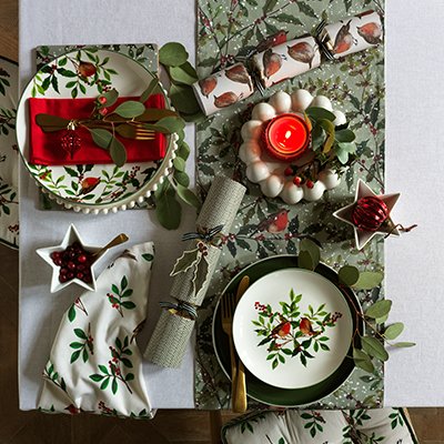 A top angle picture of Christmas dinner set placed on a white table.