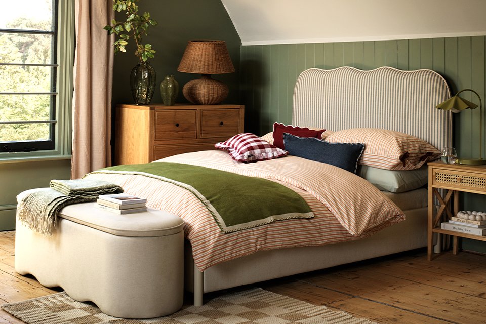 Green room with strped headboard and green patterned accessories.