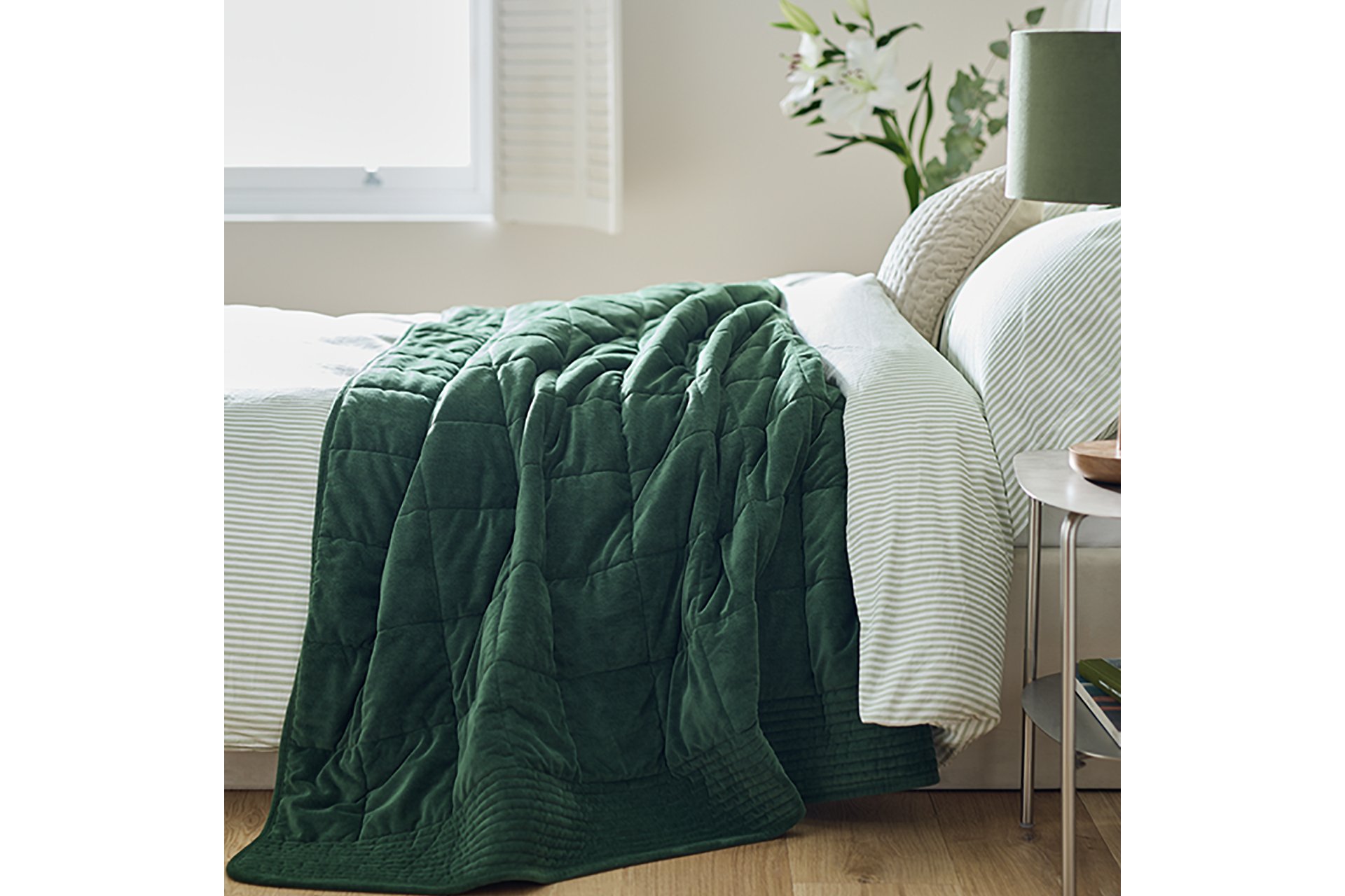Habitat green, velvet quilted bedspread used to make a bed. 