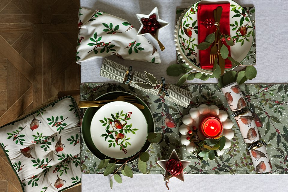 Dark circle wooden dining table with green plant on top and green walls.