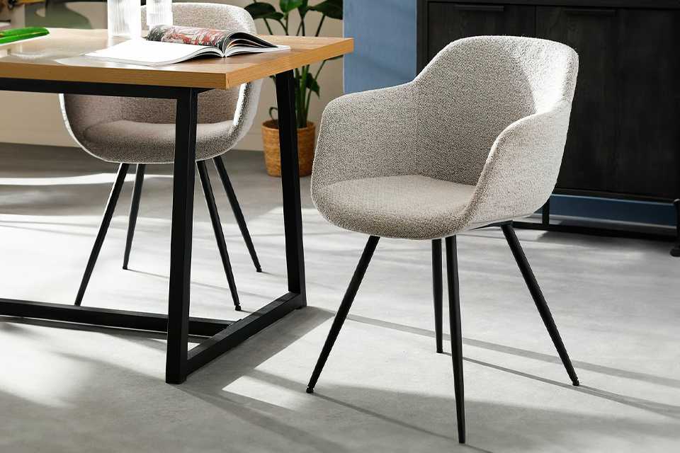 Grey fabric dining chair with black metal legs.