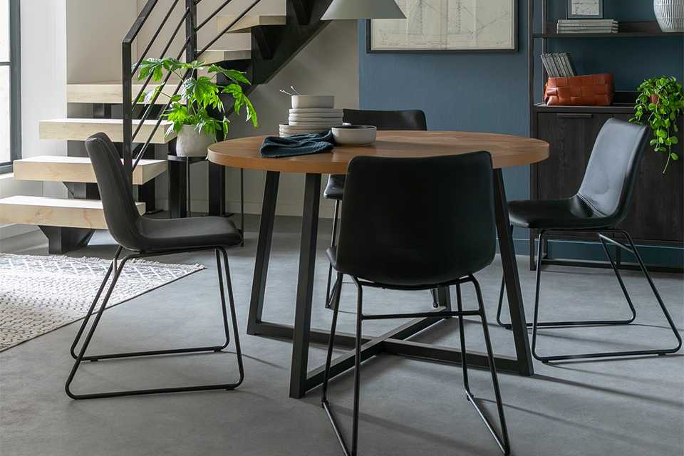 Circular wooden dining table with black metal legs and 4 black chairs.