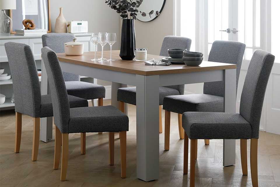 wooden extending dining table with grey legs and 6 grey chairs.