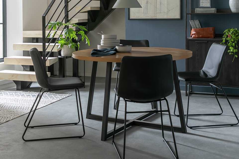 Metal dining table with circular wooden top and 4 black faux leather joey chairs.