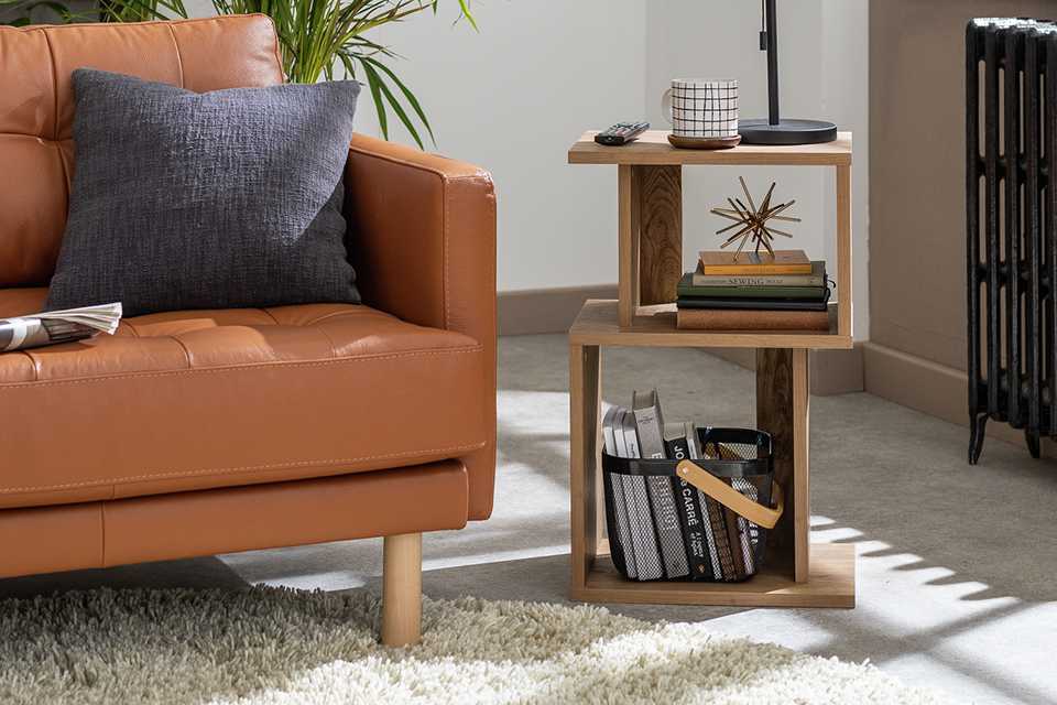 Wooden side table with a black lamp next to a brown sofa.
