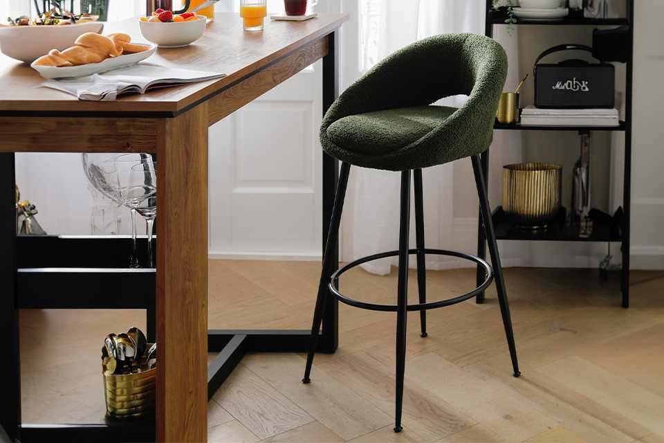 Green padded cushion bar stool seat with black metal legs.