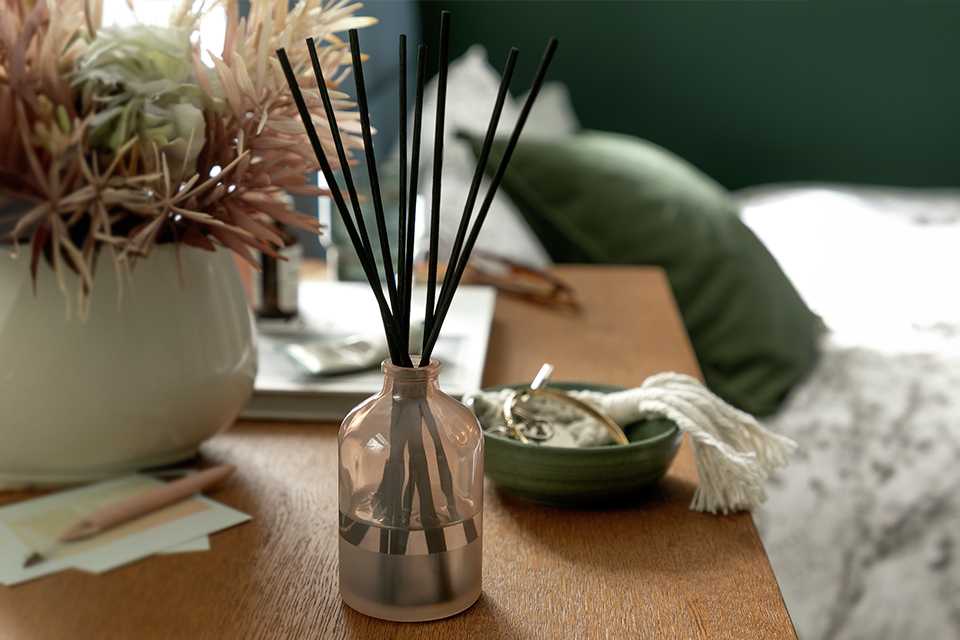 Scented diffuser on a wooden bedside table.