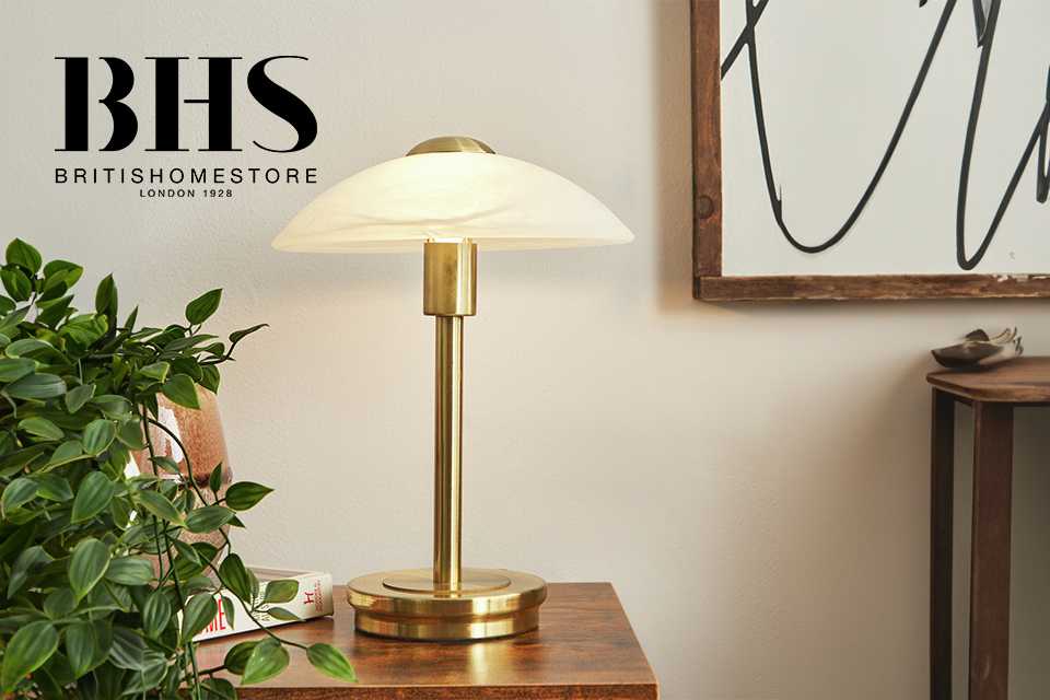 A gold finish table lamp on a wooden side table. 