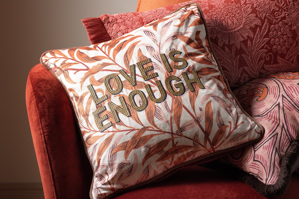 Love is enough text cushion on orange floral background.