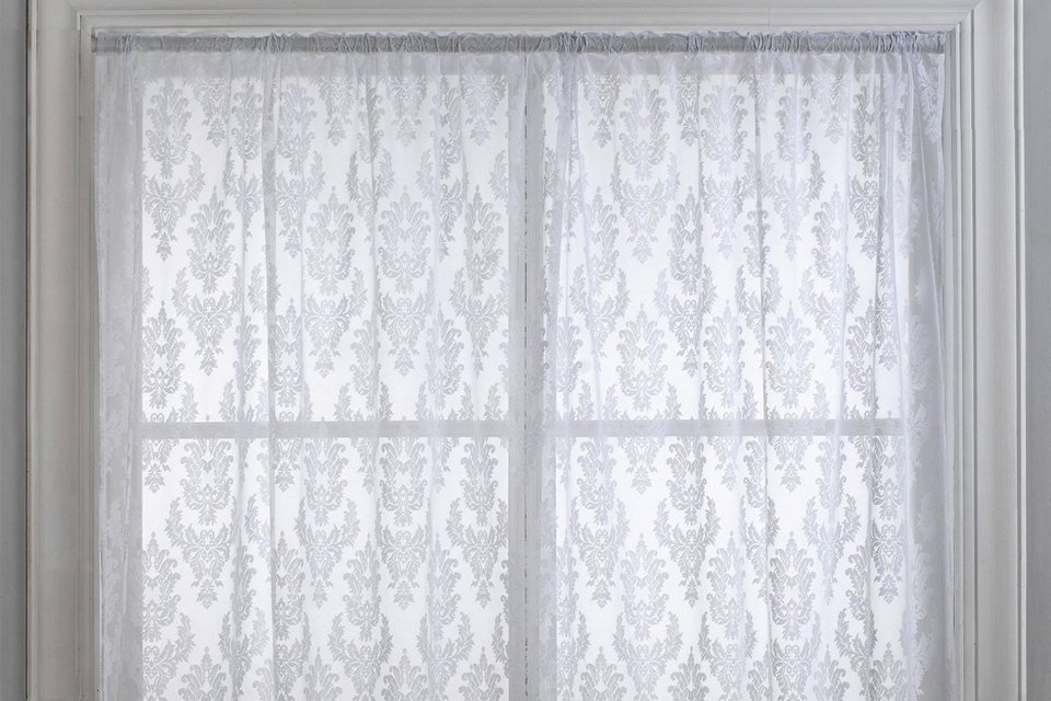 An Argos Home Damask net pencil pleat white floral curtain on a curtain track.