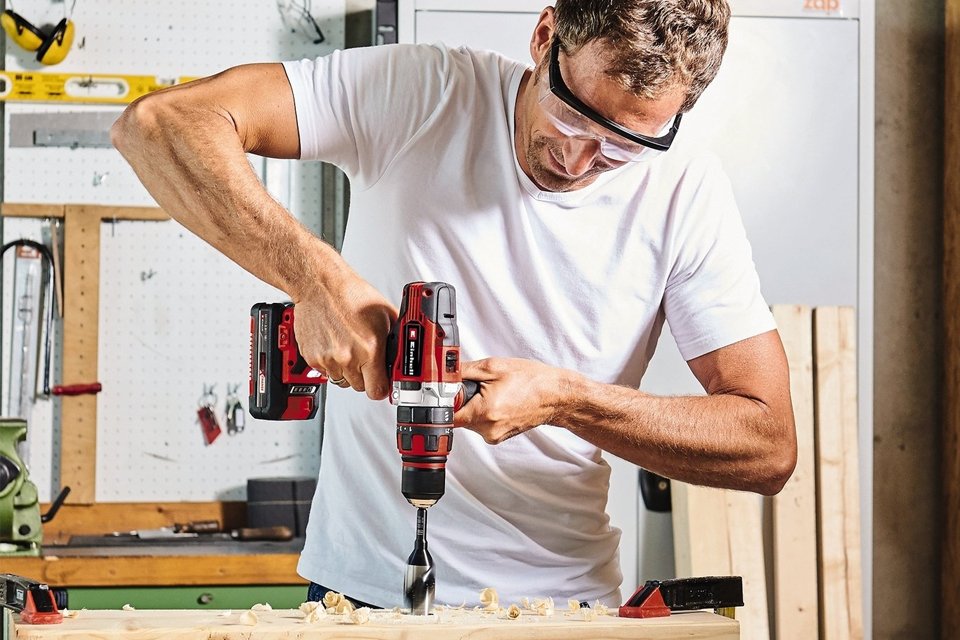 A man using Einhell Power X-Change Cordless Combi Hammer Drill - 18V.
