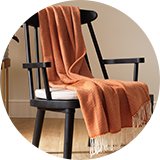 Orange throw draped over a black wooden chair.