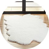 White shaggy fur sheepskin rug on a wooden floor.