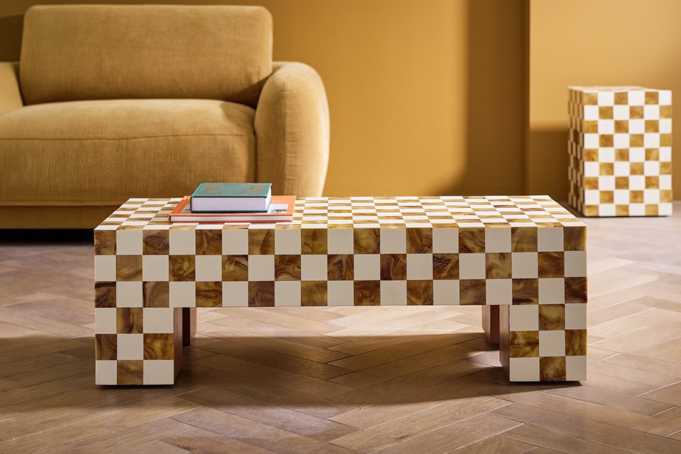 Yellow velvet sofa with checker coffee table in living room.