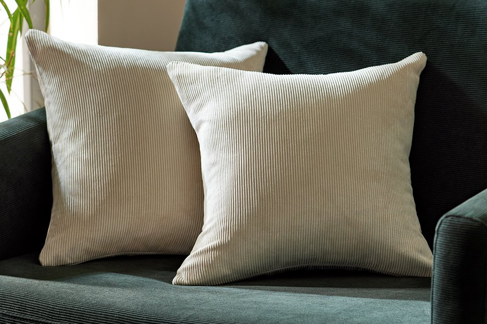 Two cushions on a sofa covered with Habitat oatmeal cushion covers.