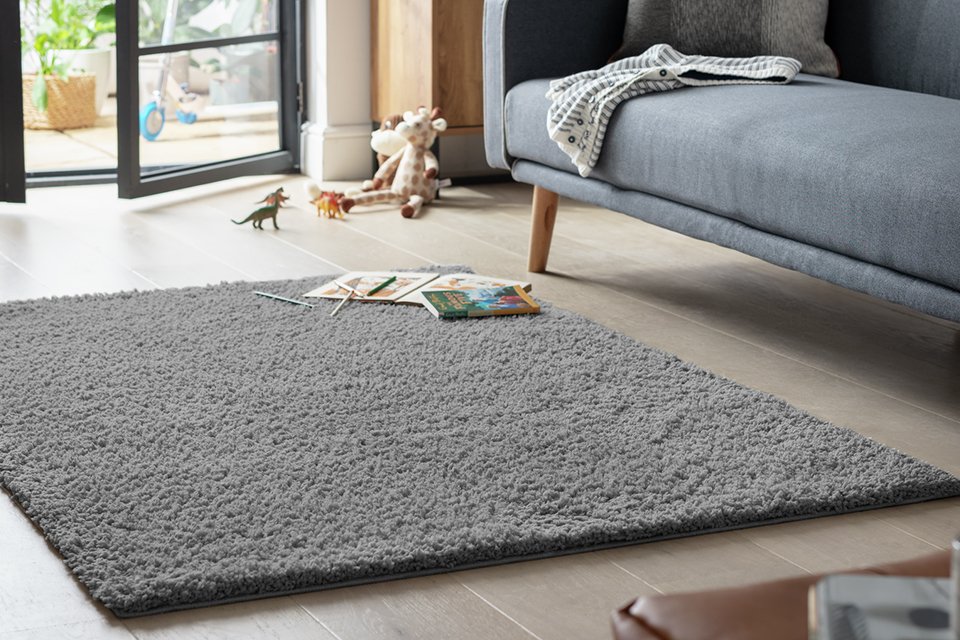 A Habitat grey rug in a living room next to a sofa.