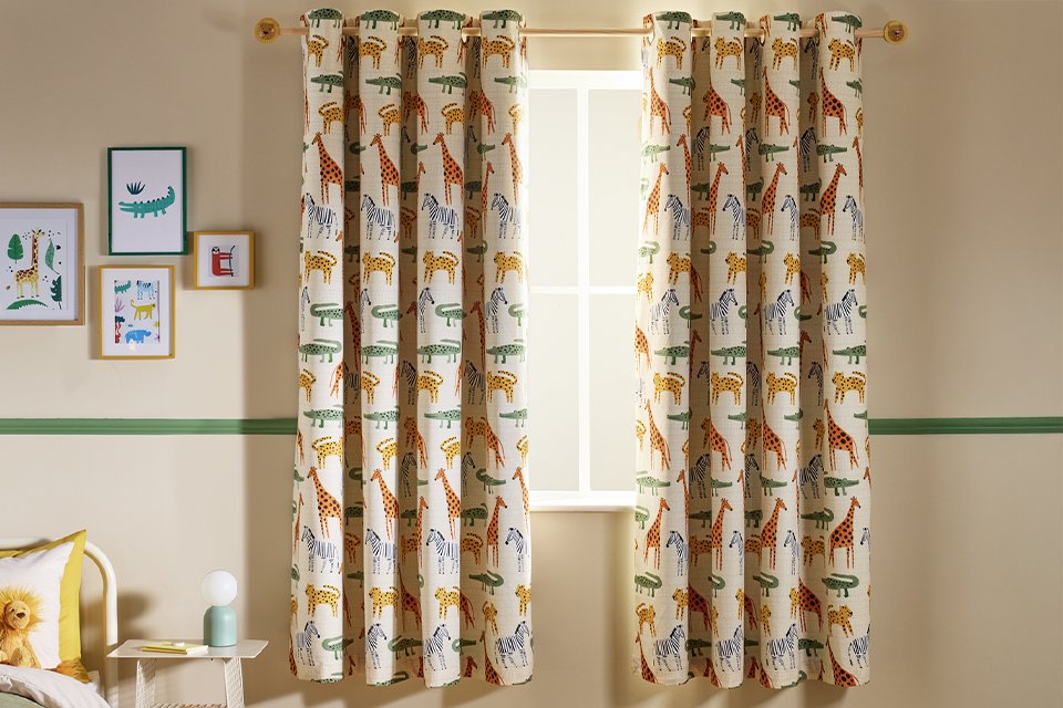 A Habitat kids' safari print eyelet curtain in cream on a bedroom window.