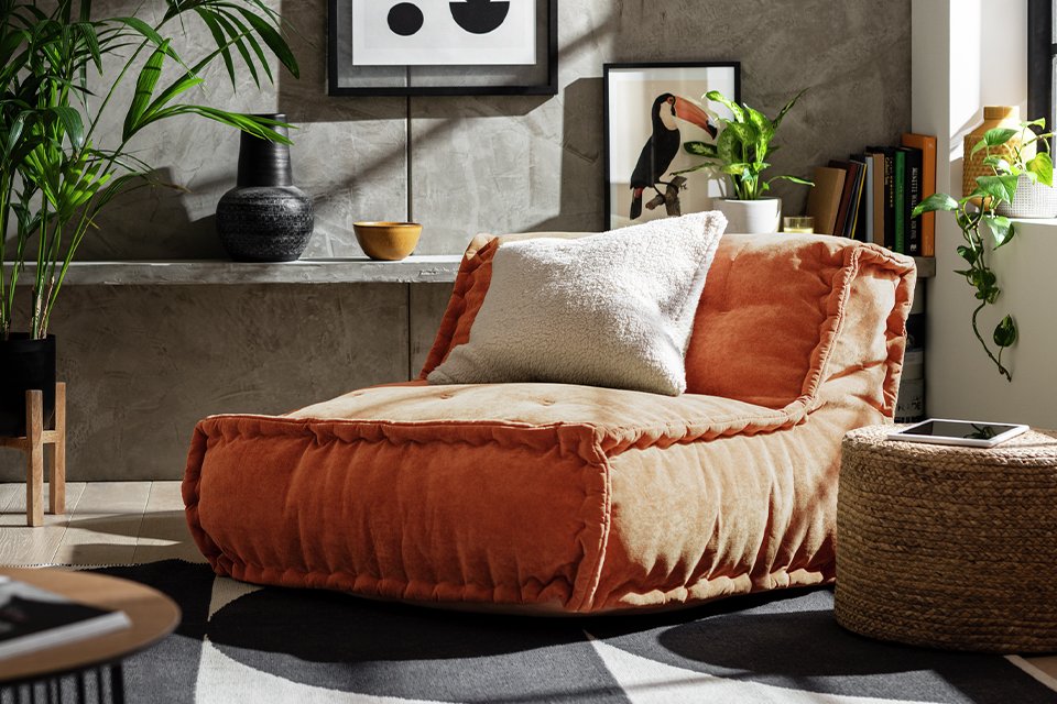 A Habitat rust quilted bean bag with a cushion on it.