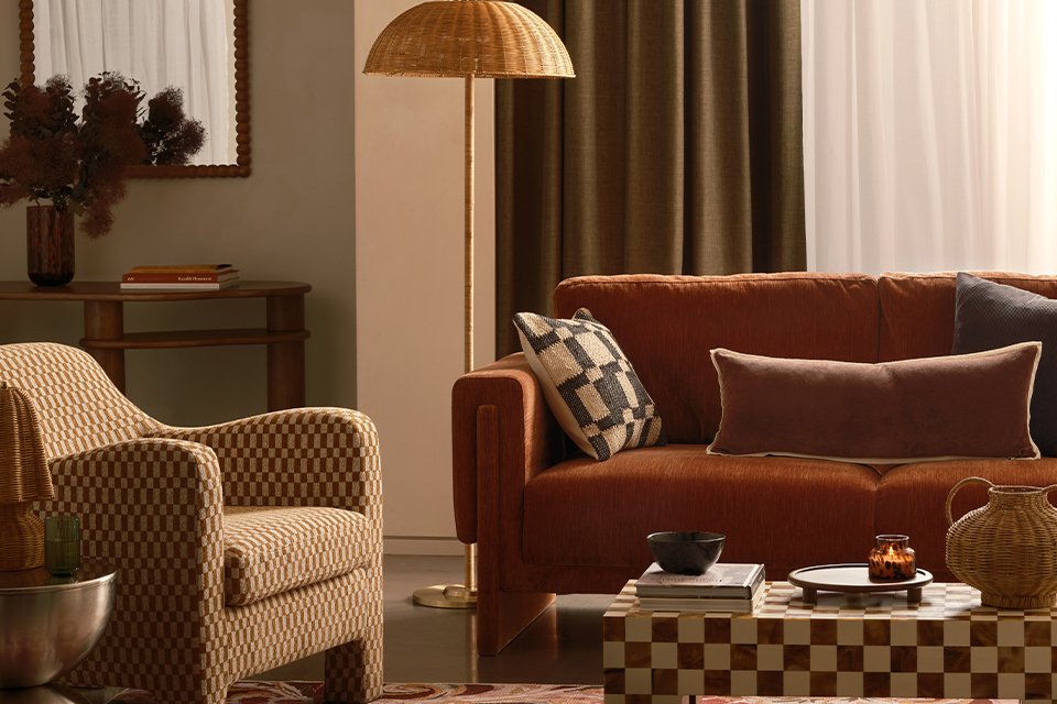A Habitat armchair next to a sofa and a patterned coffee table with a book placed on top of it.
