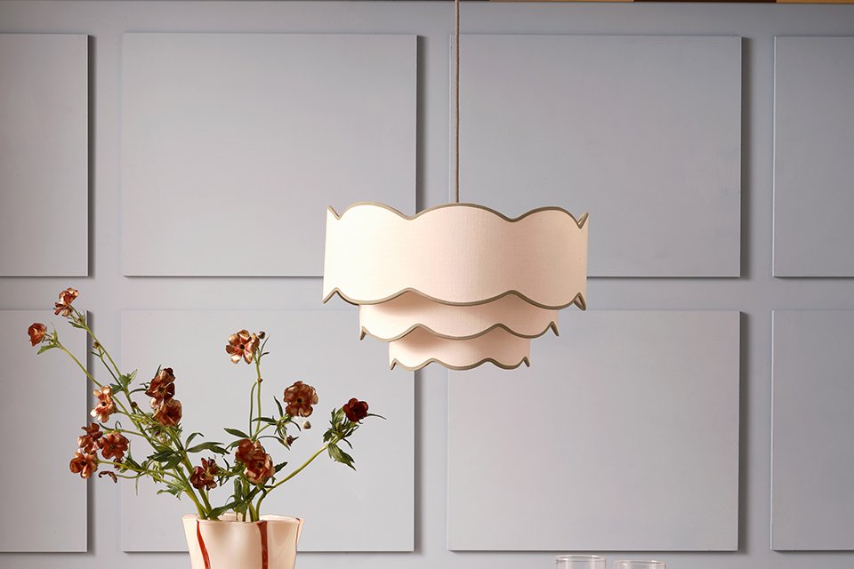 A Habitat ceiling light in a dining room above a table with plates, glasses and flowers in a vase on top of it.