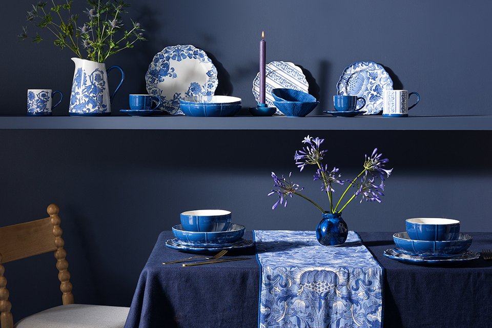 Blue dining room with morris tablware in blue chine floral print and blue tablecloth.