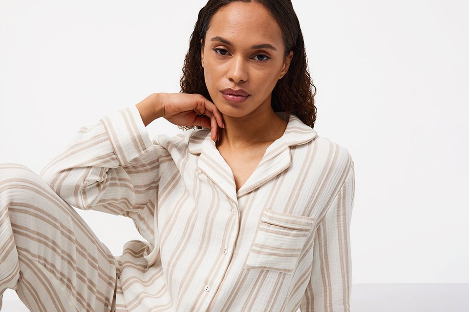 A woman wearing Tu Clothing striped pyjama shirt and matching trousers in beige colour.