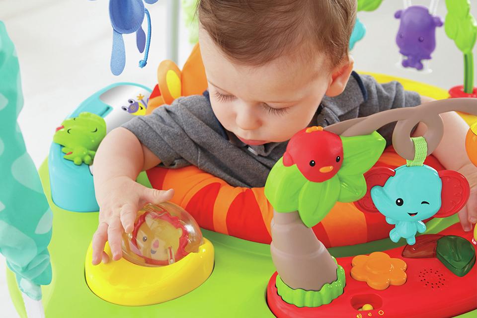 A baby plays with toys in a bouncer.