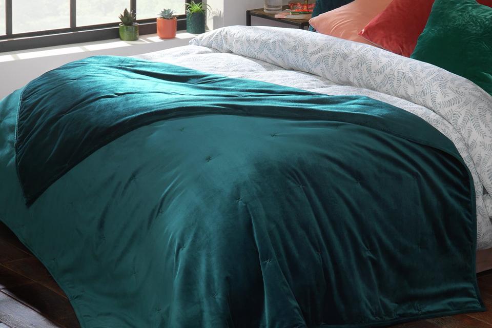 Teal green throw on top of double bed.
