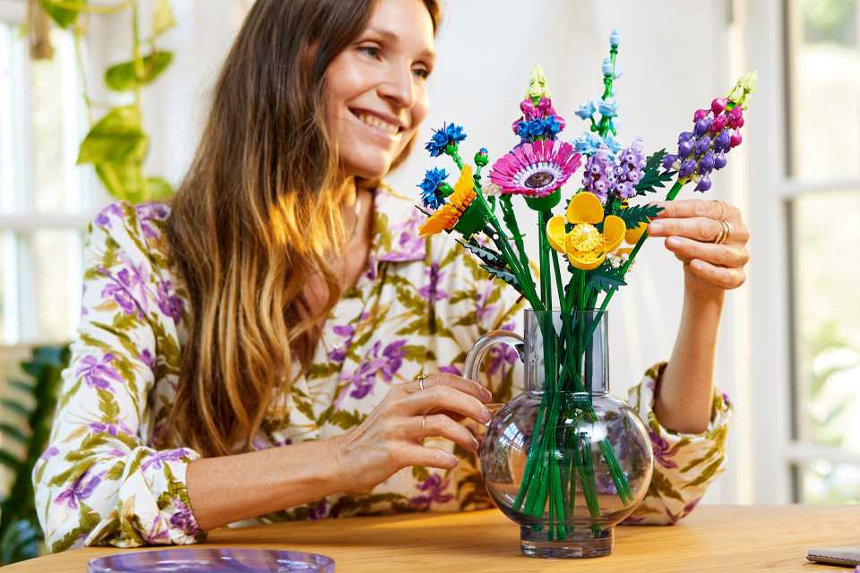 A woman looking at a LEGO® Icons Wildflower Bouquet Flowers Set for adults.