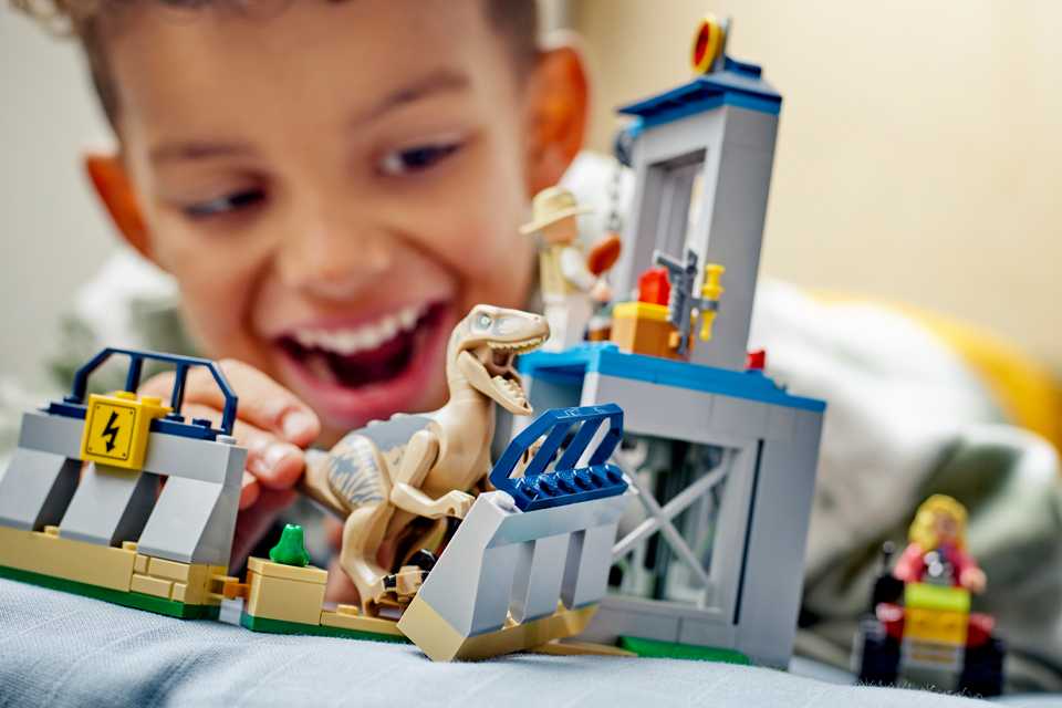 Close up shot of a young boy building and playing with LEGO Jurassic World set.