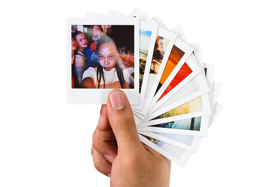 A person holding a bunch of photos printed on instax™ SQUARE film.