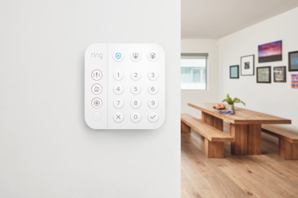 Ring Alarm keypad installed on a whilte wall in a living room setup. 