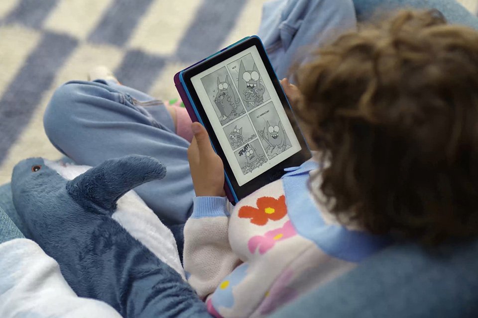 A child reading an e-book on a blue Kindle kids' e-reader. 