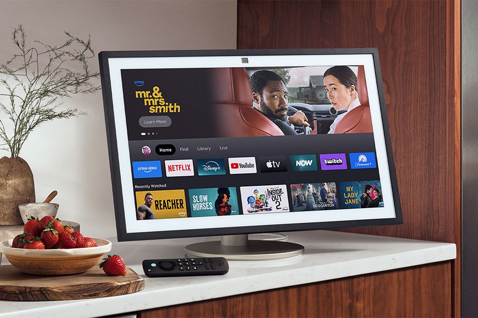 Amazon Echo Show 21 smart display with other things on a table top. 