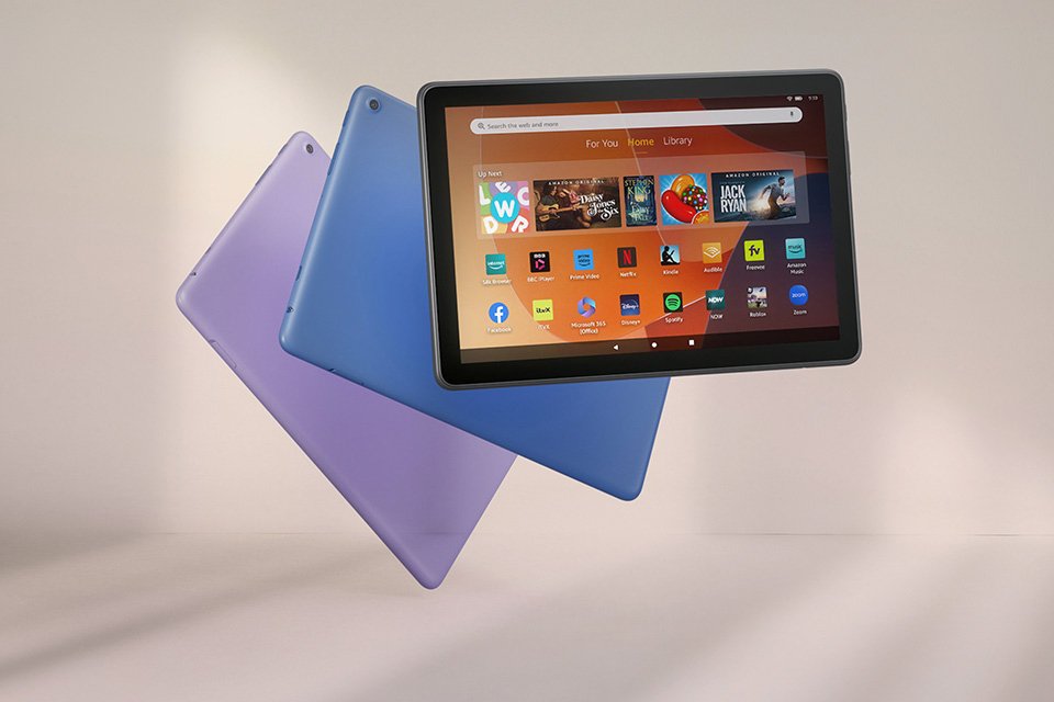 Three Amazon Fire tablets in purple, blue and black against a pinkish grey background. 