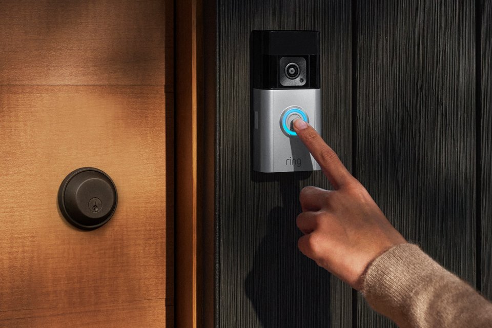 A person pressing a Ring Battery Video Doorbell Pro installed at the house entrance. 
