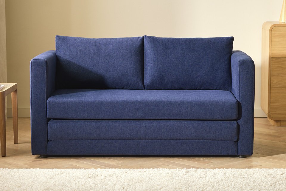 A split image with a blue Argos Home fabric sofa bed placed in a room on one side and opened out on the other. 