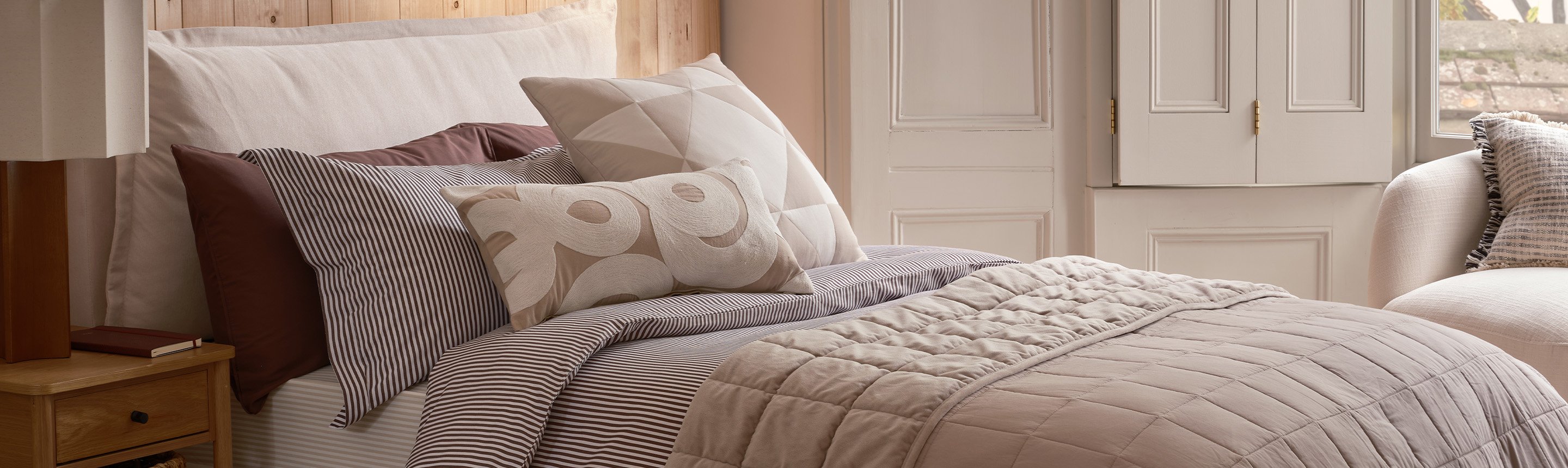 A cosy bed made with a duvet and some pillows.