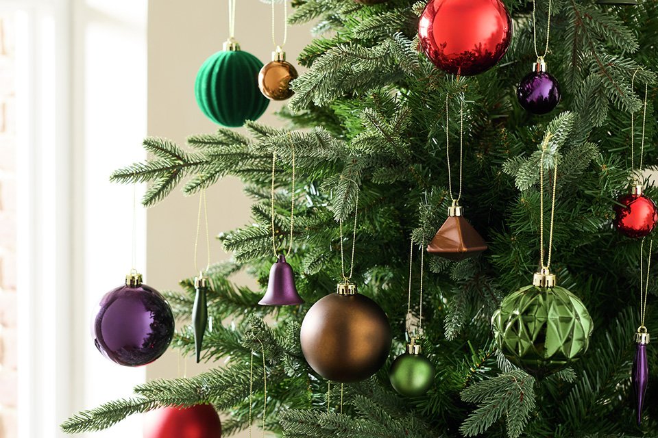 Colourful Christmas baubles hanging on a Christmas tree.