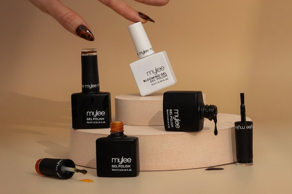 A hand with brown nail polish on the nails next to a Mylee Tortie nail art gel polish set.