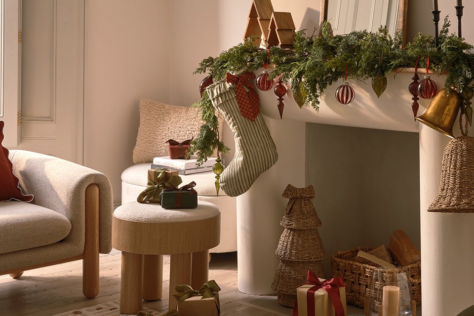 A living room decorated with Christmas decorations, a stocking over the fireplace and some gifts placed all around.