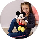 A girl holding a Mickey Mouse soft toy and smiling.
