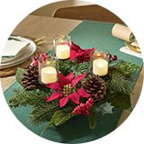 An Argos Home Poinsettia and Berry Centrepiece Wreath with Candle Holder.