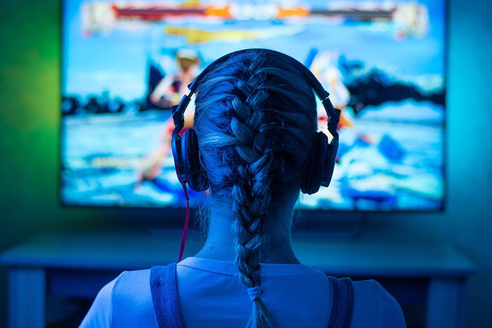 A girl playing a video game wearing headsets. 