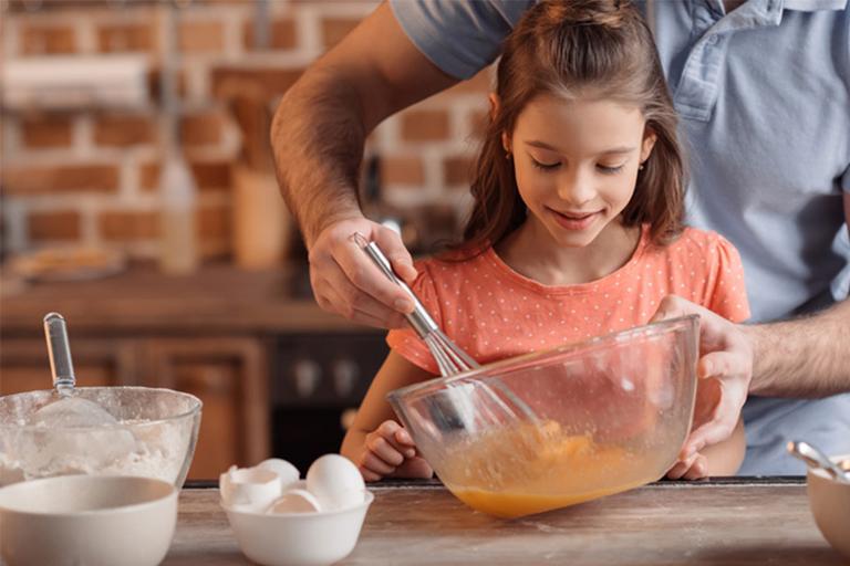 A father and daughter whisk up a cake mixture.