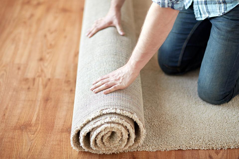 Close up of someone unrolling a rug.