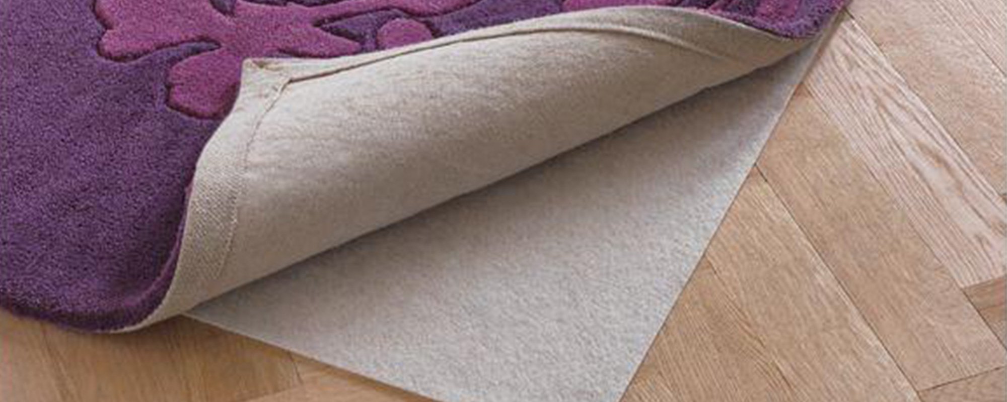 A non-slip rug underlay beneath a purple rug.