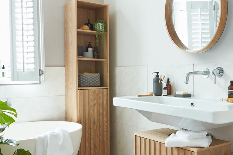 A white fitted bathroom with wooden furniture.